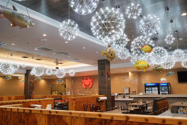 A restaurant interior with wooden booths, a counter, and hanging spherical light fixtures.