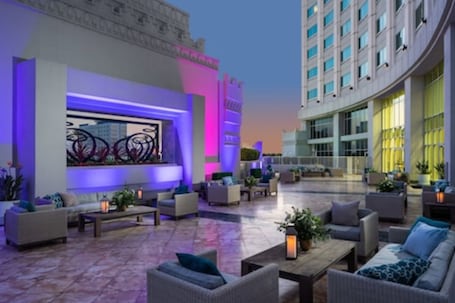 A spacious outdoor lounge area with multiple seating arrangements and a large illuminated artwork display.