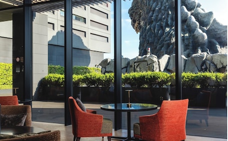 A hotel entrance with a brick facade, outdoor seating area, and potted plants.