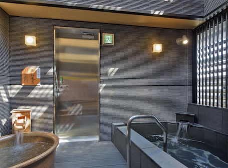 A hotel entrance with a brick facade, outdoor seating area, and potted plants.