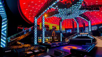 A modern venue with a central stage, seating areas, and a distinctive geometric ceiling design.