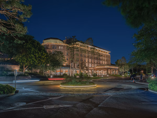 A well-lit hotel with a roundabout, landscaped greenery, and a parking sign.