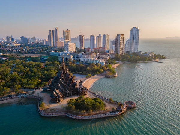 A coastal cityscape with high-rise buildings, a temple complex, and a curved waterfront promenade.